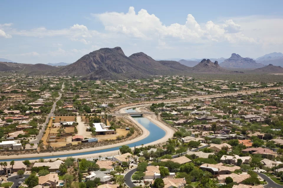 Aerial view of irrigation canal winding through Scottsdale, Arizona suburb with mountains in background